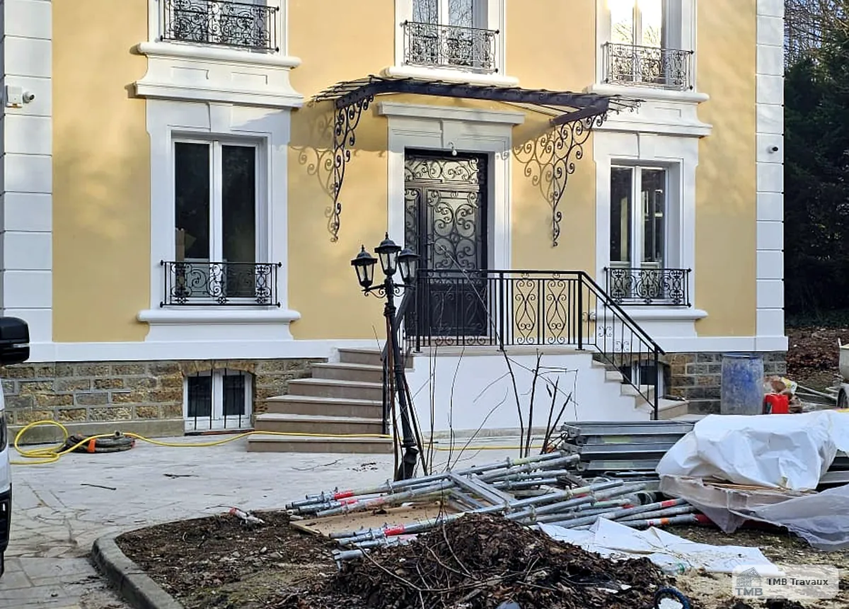 Maison rénovée avec façade propre et menuiseries sombres.